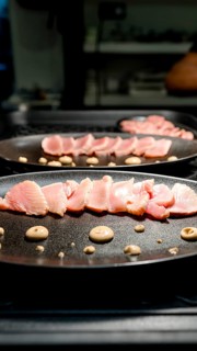 Thinly sliced seafood artfully arranged on a black plate with decorative sauce dots, perfect for a