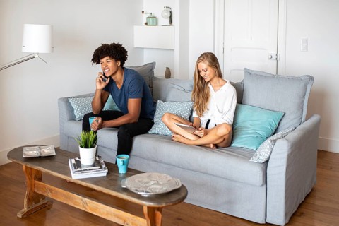 A couple enjoys a relaxed afternoon at home. One person is using a smartphone while the other