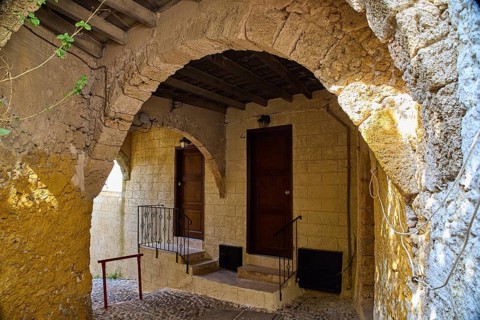 Stone arch leading to two rustic doors in a historic building with yellow walls under natural