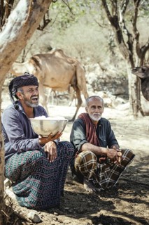 Ali on the camel farm of Sheikh Ahmed Ali Al-Mahrit drinks the fresh camel milk with his neighbour