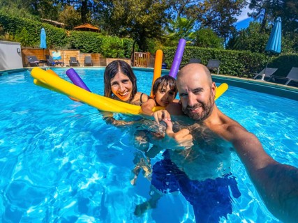 Family of three, parents and child, making a cheerful selfie together in a vibrant blue swimming