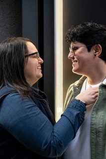 A lesbian couple joyfully smiling at each other, showcasing affection and connection. Their