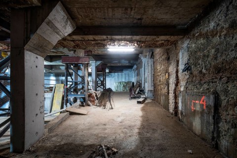 An industrial basement under construction, featuring support structures, exposed beams, scattered