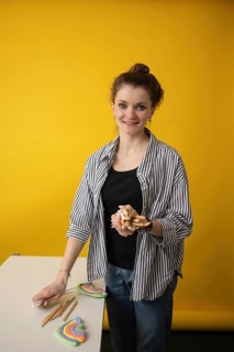 Young woman teaching a creative art lesson using colorful clay and craft tools. She holds various
