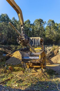Vertical photo of heavy machinery recycling wood outside a a recycling plant