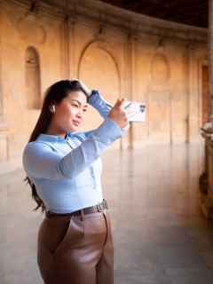 A woman is captured taking a selfie inside an ornate, historic building, showing a blend of modern