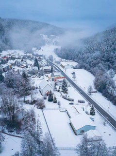 A village with a church and streets, surrounded by a snowy landscape and forests, Enzklösterle,