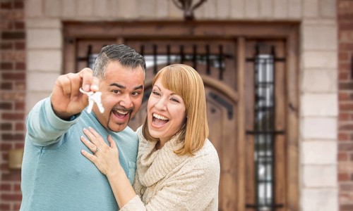 Mixed Race Couple In Front of Front Door of New House Holding Keys