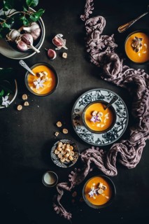 Top view of a beautifully styled table featuring creamy autumn soup garnished with flowers and