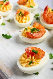 Boiled eggs stuffed with yolk and seasoned with mayonnaise, stuffed eggs with shrimp, on a white