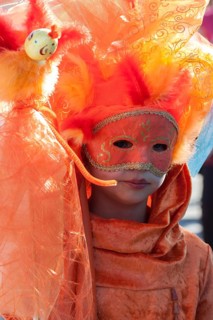 Child with Venetian carnival mask and costumes at the Venetian fair on the historic market square,