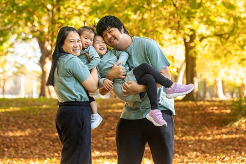 A joyful Asian family enjoying a sunny autumn day in a park. Smiling parents and children dressed
