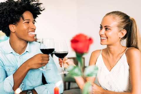 A joyful couple clinks wine glasses amid a romantic dinner setting, showcasing happiness and
