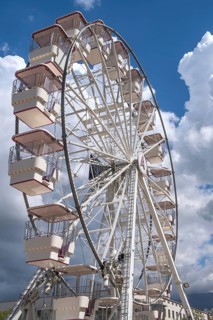 A large Ferris wheel with numerous cabins in front of a partly cloudy blue sky, Tirana, Albania