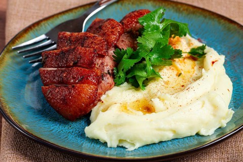 Roast duck breast, sliced with mashed potatoes, on a plate, close-up, no people