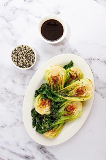 Grilled bok choy served with soy sauce and sesame seeds, on a white plate, homemade, no people