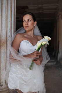 A bride in a stunning white gown holds a bouquet in an ancient villa in Treia, Macerata, Italy,