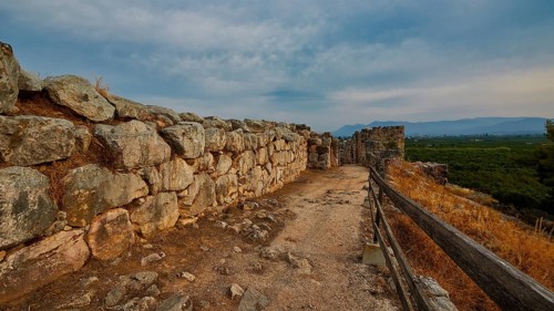 Cyclopean wall, wall of stones along a path on a hill with cloudy sky, Tiryns, ancient city in