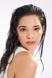 Close-up portrait of a young female model with wet hair and fresh skin, looking directly at the
