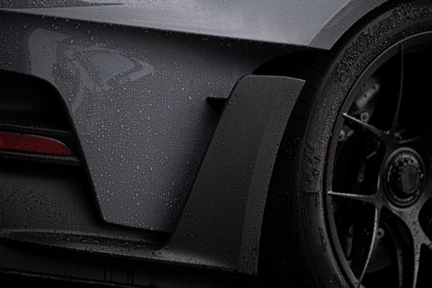 A close-up image focusing on the detailed elements of a wet sports car, showcasing its sleek design