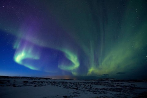 Aurora borealis in green colors over snow covered landscape at night, Lapland, Finland