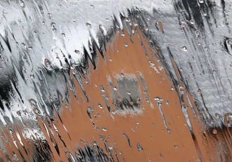 Continuous sleet on a window pane with an unclear view of a house in winter, Witten, North