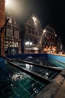 Half-timbered houses and fountains at night, atmospheric lighting emphasises the historic