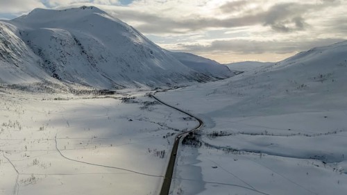 Aerial view showcasing a stunning Nordic landscape, featuring a winding road cutting through vast,