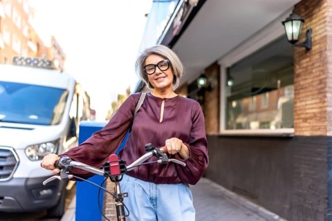 Smiling senior woman cycling through city streets, embracing an active, sustainable urban lifestyle