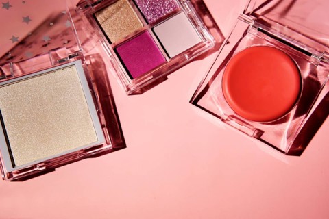 Top view of vivid makeup products including a shimmering powder, a four-shade eyeshadow palette