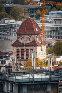 An old church with a red dome stands in contrast to modern buildings in an urban autumn scene,