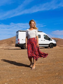 A woman enjoys the freedom of van life in Fuerteventura, Canary Islands. With a camper van parked