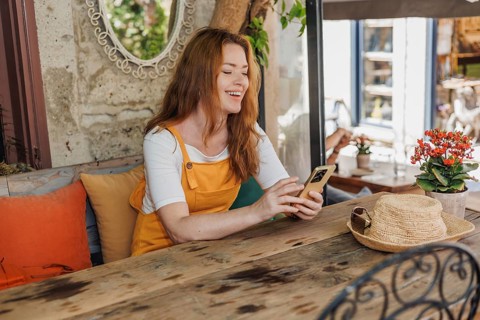 A cheerful woman, dressed in orange and yellow, joyfully explores an old city in Cesme, Turkey. She