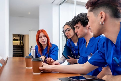 Group of young medical professionals and students in blue scrubs having an informal discussion and