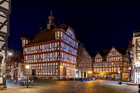 Atmospherically illuminated half-timbered houses in an urban setting at night on a square, The