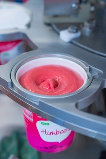 Pink raspberry ice cream is filled into a vegan sundae, ice cream production farm ice cream,