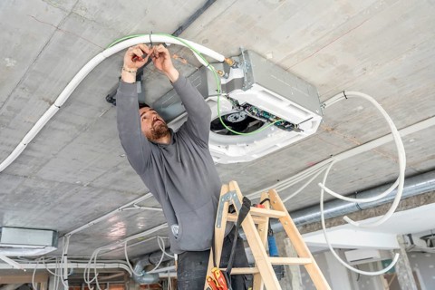 Professional hvac technician working on a modern air conditioning unit installation in a