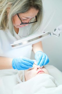 A skilled esthetician cosmetologist uses a metal extractor tool to perform a deep pore cleansing