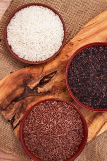 Set of red and black and white rice, in a bowl, on a wooden surface, rustic style, top view