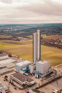 The picture shows a tall industrial building in an agricultural area under cloudy sky,