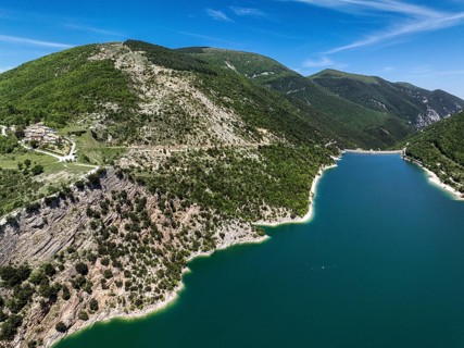 An aerial shot of Lago di Fiastra in Italy showcases its turquoise water bordered by lush green