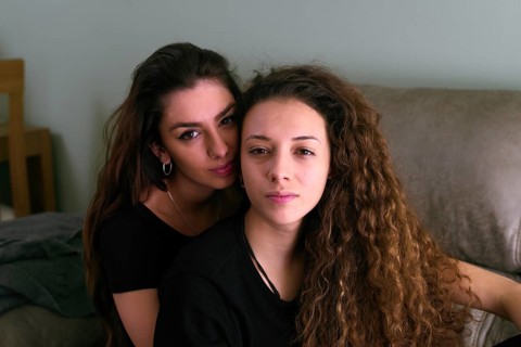 A female gay couple relaxing closely on a sofa, exuding warmth and affection towards one another,