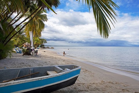 Sandy beach beach, coconut trees and boat at Playa Blanca, Izabal Department, Guatemala