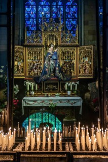 Maastricht, Netherlands, Altar in a church with a figure of a saint, surrounded by burning candles