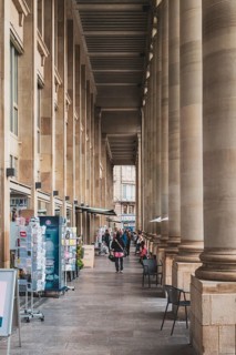 Elegant arcade with tall columns and people walking in a historic city area, Königsbau am