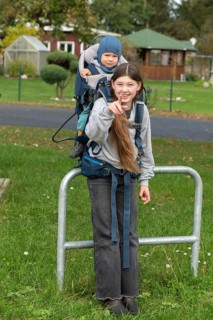 Girl, 10 years old, carrying her little nephew in a back carrier, Mecklenburg-Vorpommern, Germany