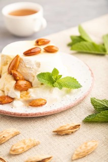 Ricotta cheese with honey and almonds on gray concrete background and linen textile. side view,