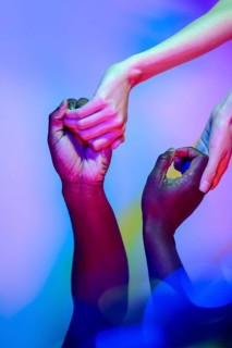 A diverse group of hands reaching out and connecting, illuminated by colorful lights, symbolizing