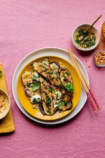 Top view of a colorful dish featuring roasted courgettes topped with mozzarella, basil, toasted