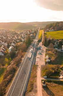 View of a village with railway line and adjacent fields in sunset light, Hermann Hesse Railway,